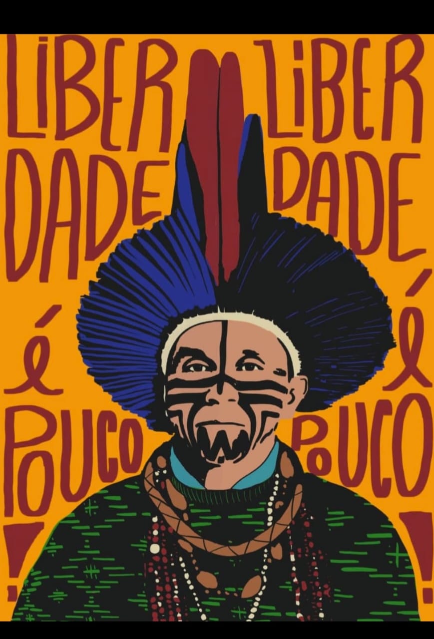 Ilustração em estilo gráfico de Mãdy Pataxó visto de frente, usando um grande cocar de penas azuis com duas penas centrais vermelhas. O rosto apresenta pinturas corporais pretas simétricas e expressão séria. A pessoa veste uma roupa verde com grafismos e diversos colares de sementes e miçangas. Ao fundo, em um plano laranja intenso, aparecem em letras grandes a frase "Liberdade é pouco!", repetida dos dois lados da figura. A composição utiliza cores vibrantes e forte contraste para transmitir uma mensagem de mobilização em defesa da liberdade e dos direitos indígenas.
